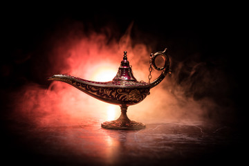 Lamp of wishes concept. Antique Aladdin arabian nights genie style oil lamp with soft light white...