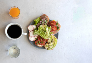Plate with sandwiches or tapas on a gray background with drinks black coffee, juice, water, the concept of a shared breakfast with friends, a healthy snack, quarantine, general breakfast