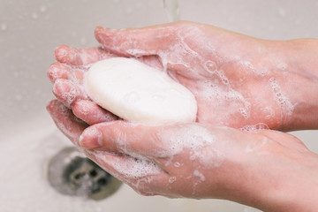 A man holds soap in his hands. Hand washing with soap. Hands in soap with foam closeup. Antibacterial agent for combating coronavirus.