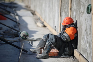 Sunny day. Worker in uniform sleeps at a construction site during working hours.