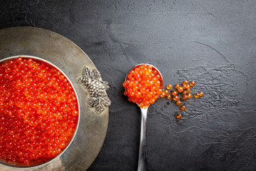 Delicious red caviar in vintage plate, top view, dark background
