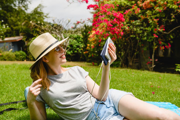 Happy woman with electronics outdoors charge phone