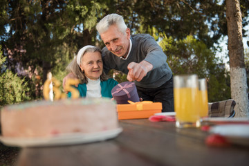 Husband hugging his wife and pointing on a birthday cake