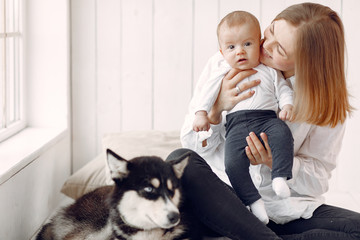 Fototapeta na wymiar Beautiful woman with child. Woman in a white shirt. Family playing with big dog.