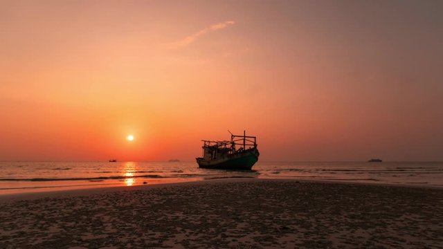 Colourful sunset behind the boat at the beach in Thailand. Timelapse of the sun that goes down at the seashore near the ocean. Concept of vacation at the beach and travelling.