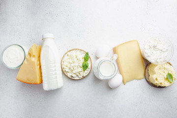 Fresh dairy products, milk, cottage cheese, eggs, yogurt, sour cream and butter on white table, top view