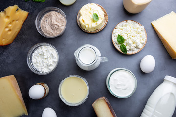 Fresh dairy products, milk, cottage cheese, eggs, yogurt, sour cream and butter on black background, top view