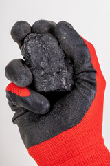 Brown coal nuggets held in hand. Material for heating homes on a work glove.