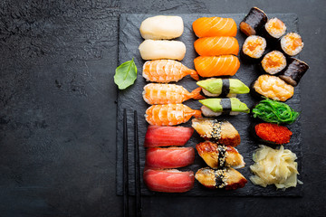 Set of sushi and maki with soy sauce over black background. Top view with copy space