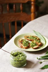 Pesto from wild garlic and fried toast from baguette on the table. Back of chair in the background. life style food