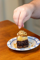 putting nut topping on a cake slice covered in caramel