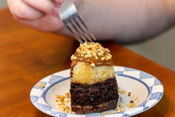 a fork and a chocolate cake slice covered in nuts