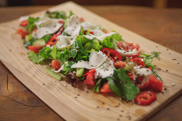 Salad on a wooden long board. Closeup on a wooden table