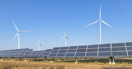 Solar panels and wind turbines generating electricity is solar energy and wind energy in hybrid power plant systems station use renewable energy to generate electricity with blue sky