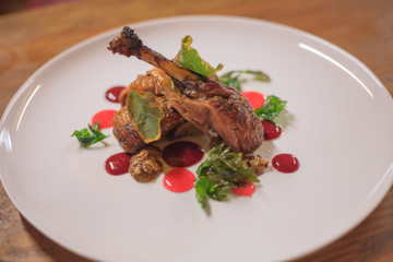 Chicken with colored sauce on a white plate. Closeup on a wooden table.