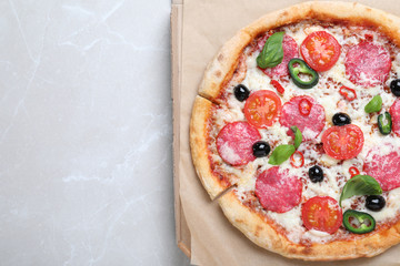 Delicious pizza Diablo in cardboard box on light marble background, top view. Space for text