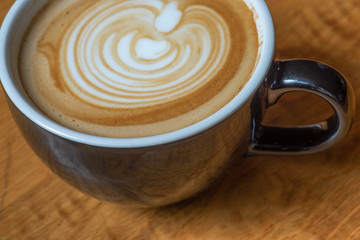 Latte in mug on wooden table with foam art