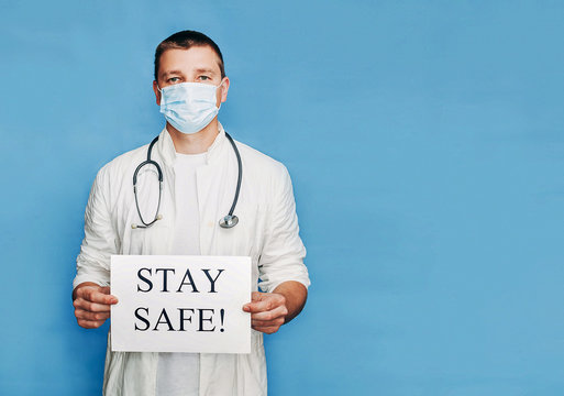 The doctor on a blue background in a white coat and in a surgical mask calls # Stay safe. COVID-19. Self isolation. Stay home, conception. Quarantine. Banner. Place for text