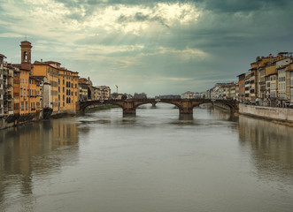Fototapeta na wymiar Panoramica de puente sobre el rio Arno en Florencia, Italia con cielo nublado