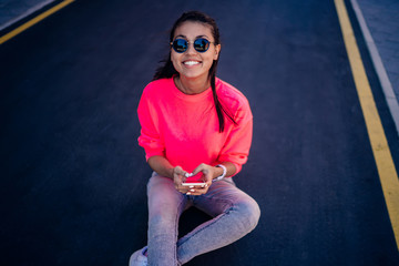 Portrait of happy hipster girl in trendy sunglasses and pink sweatshirt with copy space for brand...