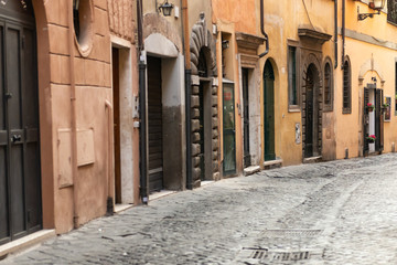 A narrow alley in the center of Rome. Medieval buildings. There's no one on the street.