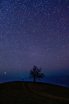 Rear view of man standing on hill under starry sky
