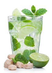 Glass of Mojito summer alcoholic cocktail with ice cubes mint and lime on white with raw lime, mint leaf and cane sugar