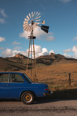 Vintage car in front of windmill on rural road