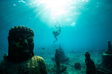 Taucher schwimmen unter Wasser in der Nähe von Buddha-Statuen