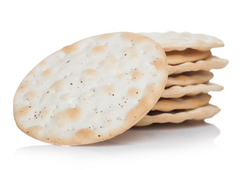 Stack of round organic crispy salty crackers on white.