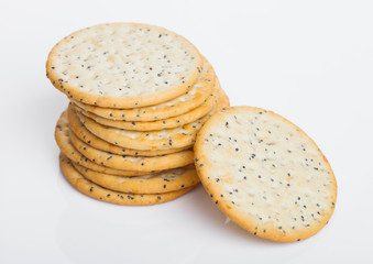 Stack of round organic crispy wheat and five grain salty crackers with seeds on white.Top view