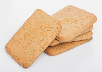 Stack of square organic crispy wheat and five grain salty crackers on white. Top view