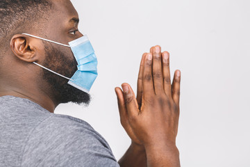 Coronavirus. African american man praying wearing hygienic mask to prevent infection, airborne...