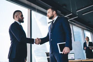 Fototapeta premium Pensive businessman shaking hand of partner