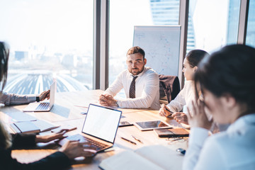 Focused coworkers having discussion and using laptop at meeting in conference room