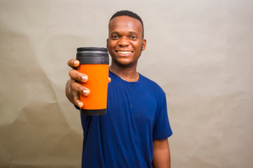 young handsome african man feeling happy as he holds a coffee cup