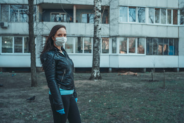 Obraz premium Portrait of young woman in medical mask on her face standing on street. Adult female covered her face with mask to protect yourself from diseases.