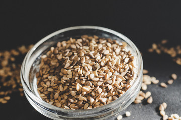 Close-up of Organic whole sesame seeds, in a small glass bowl on a black background