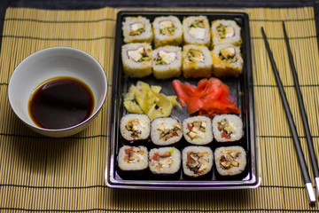 japanese cuisine different rolls with black chopsticks red pickled ginger wasabi sauce and soy sauce on the table