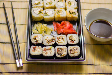 japanese cuisine different rolls with black chopsticks red pickled ginger wasabi sauce and soy sauce on the table