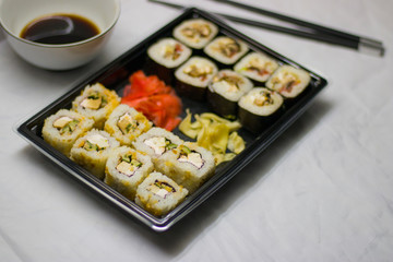 japanese cuisine different rolls with black chopsticks red pickled ginger wasabi sauce and soy sauce on the table