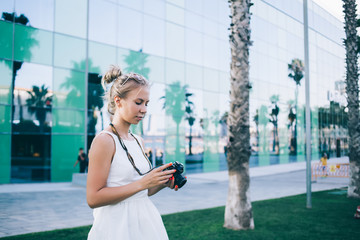 Stylish photographer examining photos on street