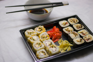 japanese cuisine different rolls with black chopsticks red pickled ginger wasabi sauce and soy sauce on the table