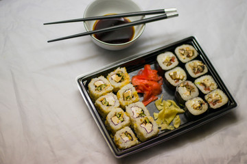 japanese cuisine different rolls with black chopsticks red pickled ginger wasabi sauce and soy sauce on the table