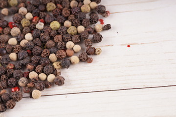 Close up of condiment on white wooden background. Bunch of different peppers on table with space for your text.