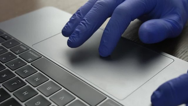 Doctor's Hand in Blue Surgical Gloves Using Trackpad Touchpad on Office Laptop