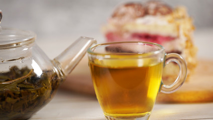 Close up of green tea in teapot and cup on white wooden table.
