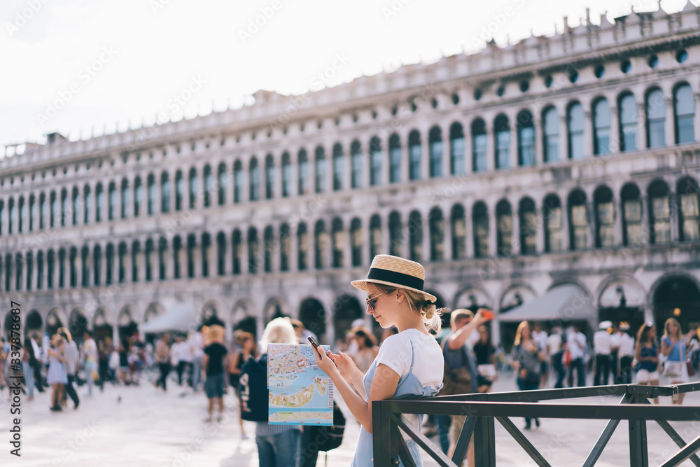 Poster trendy female tourist in straw hat networking via mobile device browsing travel app for reading info