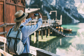 Naklejka na ściany i meble Female traveler taking picture of nature from pier