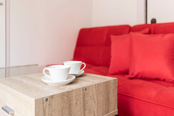 Two cups of coffee and red sofa in the living room